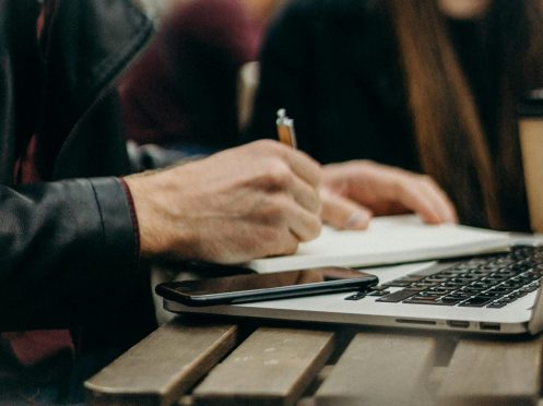 freelancer working at a table with his laptop and Everbook for great freelance analog productivity